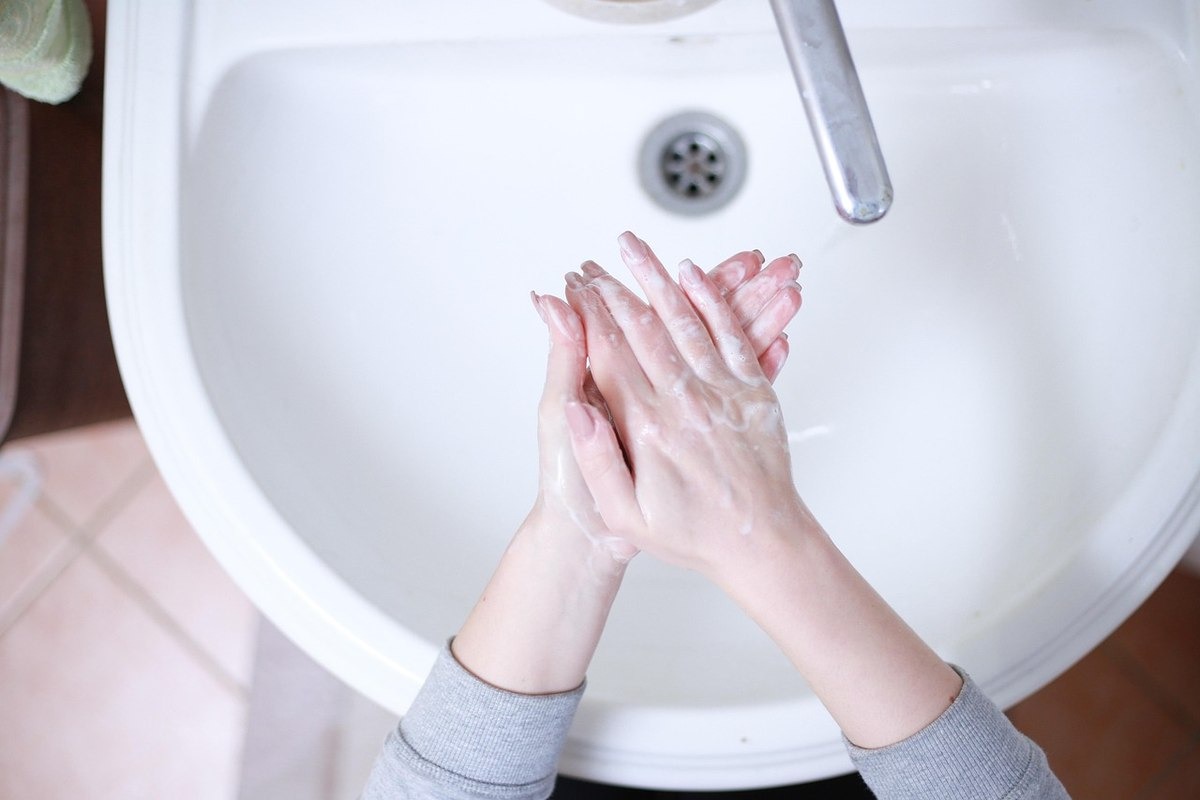 Mains mouillées et savonneuses se frottent sous un robinet d'eau courante