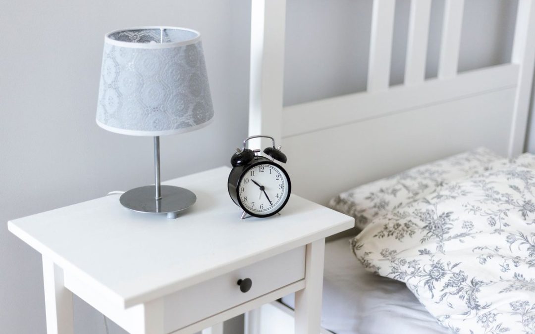 Table de nuit avec lampe et réveil, lit avec oreiller